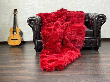 Fox Fur Blanket Throw Red - Tatifurs draped over a couch, showcasing its vibrant color and luxurious texture.
