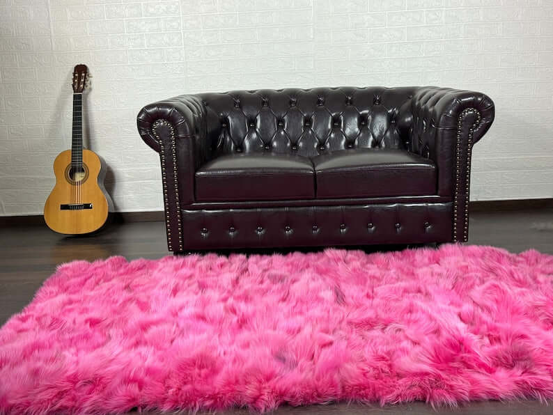 Fox Fur Blanket Throw Fuchsia - Tatifurs placed in a stylish living room with a leather couch and guitar.