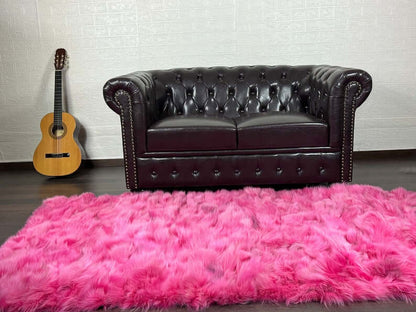 Fox Fur Blanket Throw Fuchsia - Tatifurs placed in a stylish living room with a leather couch and guitar.