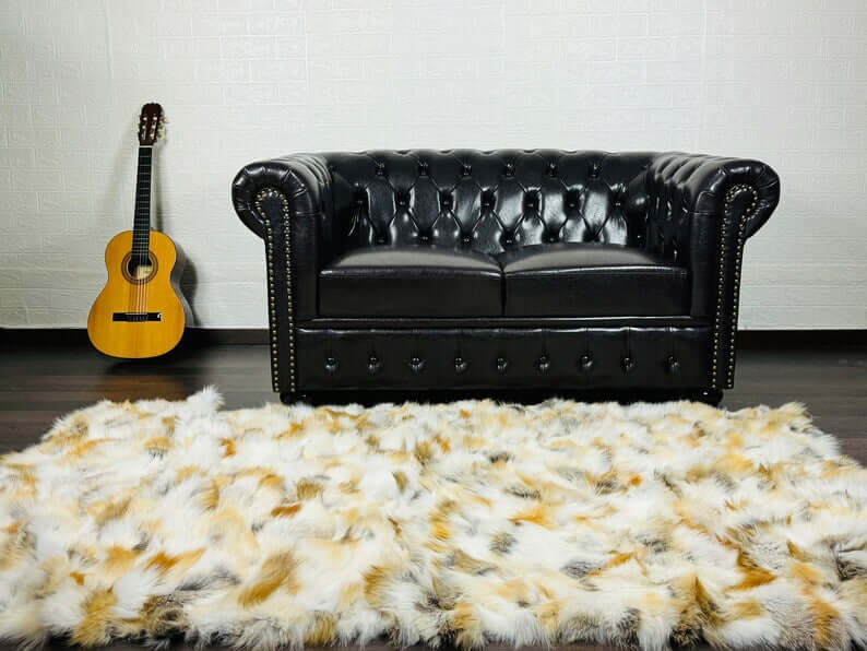 Fox Fur Blanket Throw Golden - Tatifurs on a stylish black sofa with a guitar in the background.