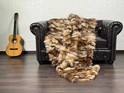 Fox Fur Blanket Throw Crystal Natural - Tatifurs draped on a dark leather couch next to a guitar.