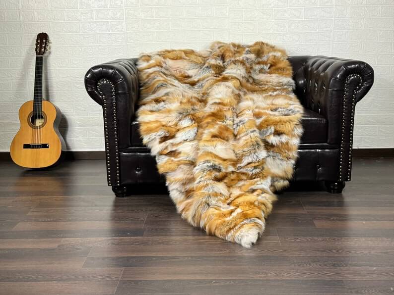 Fox Fur Blanket Throw Red Canadian - Tatifurs draped on a leather sofa with an acoustic guitar in the background.