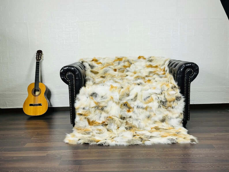 Fox Fur Blanket Throw Golden - Tatifurs draped over black leather couch with guitar nearby.