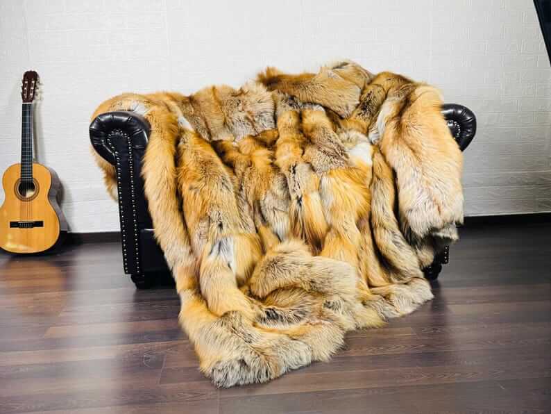 Fox Fur Blanket Throw Gold Saga Fox Natural - Tatifurs draped over a couch, showcasing fiery orange and white tones.