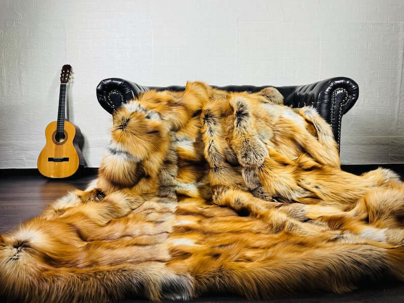 Fox Fur Blanket Throw Gold Saga Fox Natural - Tatifurs draped over a couch with a guitar in the background.