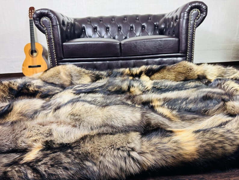 Fin Raccoon Blanket Throw Fur Natural - Tatifurs displayed on a stylish leather sofa with a guitar beside it.