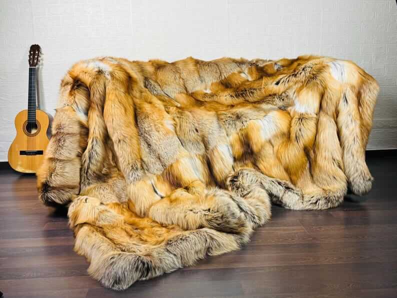 Fox Fur Blanket Throw Gold Saga Fox Natural - Tatifurs displayed on a couch with a guitar nearby.