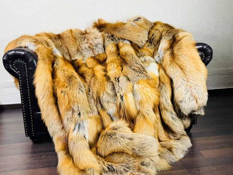 Fox Fur Blanket Throw Gold Saga Fox Natural - Tatifurs on a couch, displaying vivid orange and white tones.