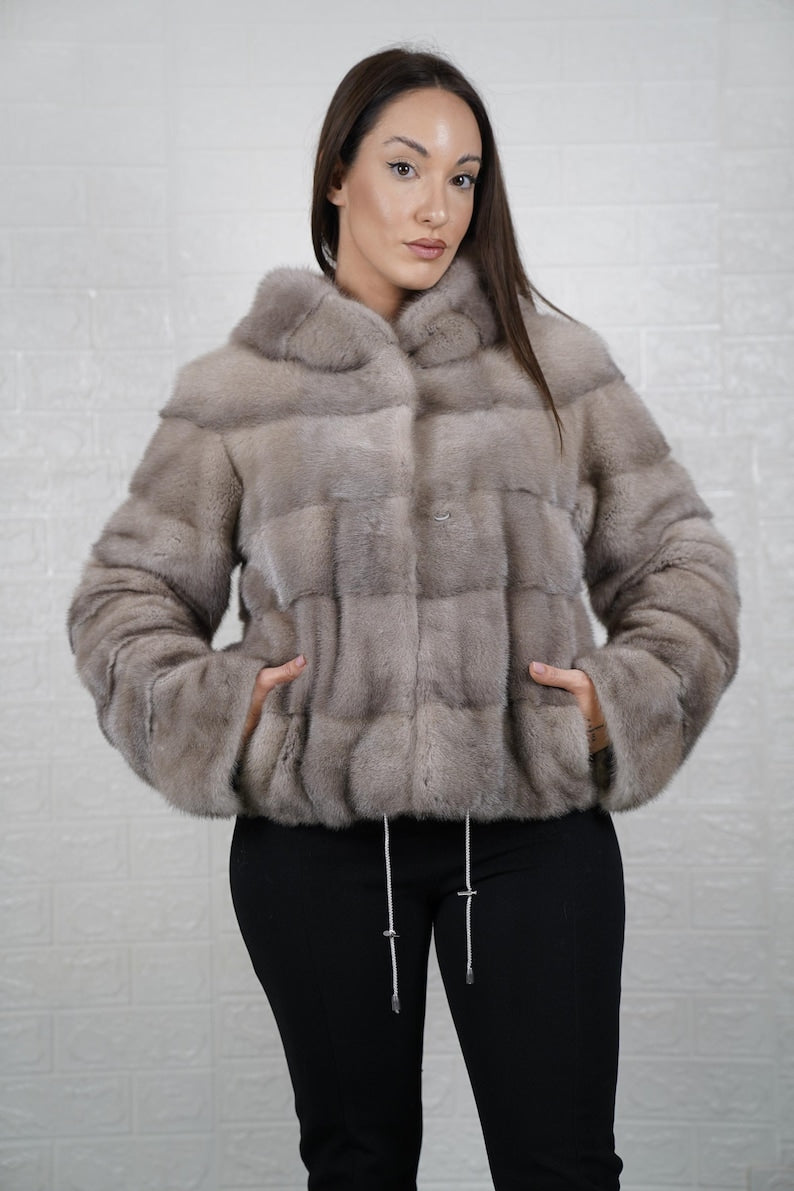 Woman wearing a mink gray fur jacket against a light gray background