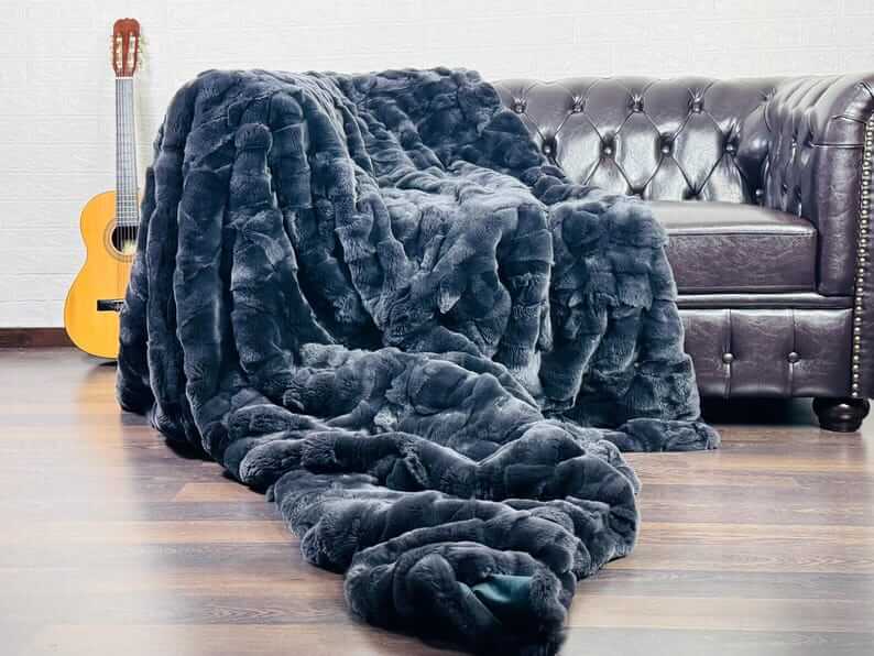 Rabbit Blanket Throw Rex Gray - Tatifurs draped on a couch with a guitar in the background, showcasing luxurious texture.