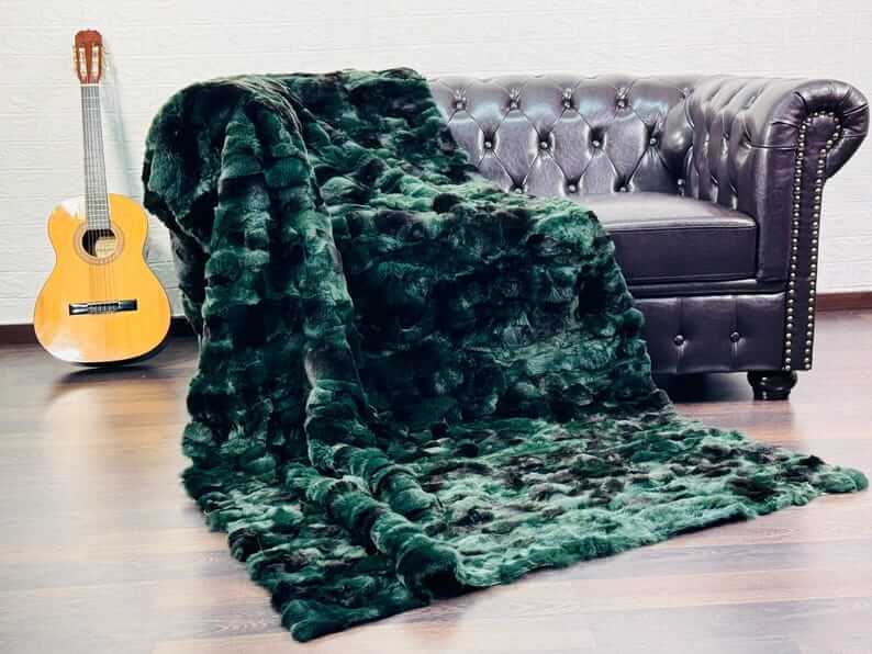 Rabbit Blanket Throw Rex Green Black - Tatifurs draped over a dark sofa with a guitar nearby.