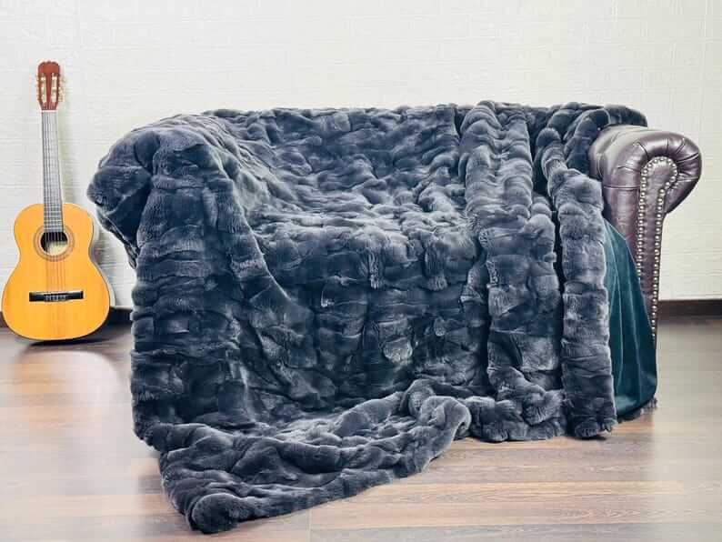 Rabbit Blanket Throw Rex Gray - Tatifurs draped over a couch with a guitar nearby, showcasing luxurious fur texture.