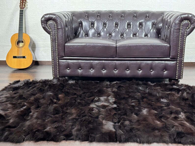 Fox Fur Blanket Throw Brown - Tatifurs displayed on a plush rug beneath a leather couch with a guitar in the background.