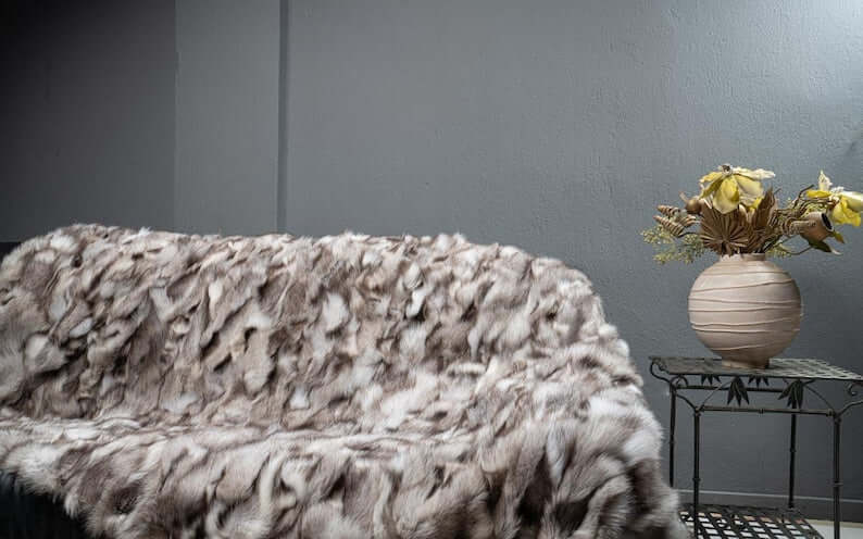 Fox Fur Blanket Throw Blue Natural Dark - Tatifurs displayed on a couch with decorative flowers.