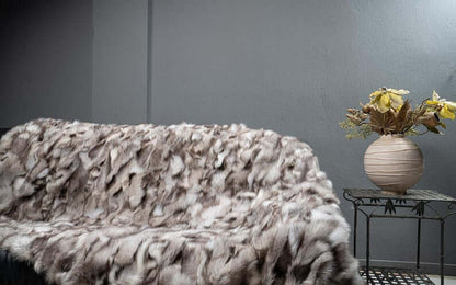 Fox Fur Blanket Throw Blue Natural Dark - Tatifurs displayed on a couch with decorative flowers.