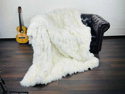 Fox fur blanket throw white draped across a bed showing pure luminous white tone and natural long pile movement in soft light
