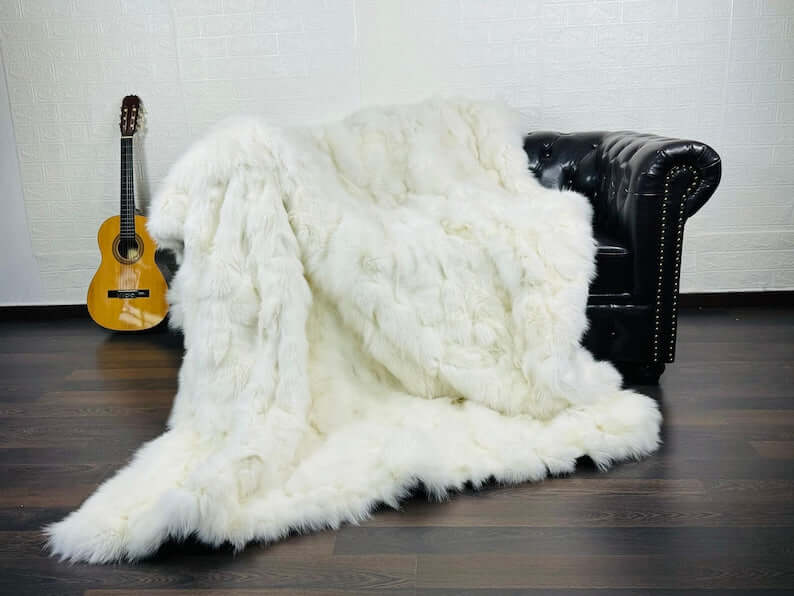 Fox fur blanket throw white draped over a pale sofa showing pure luminous white tone and long flowing fox fur pile throughout
