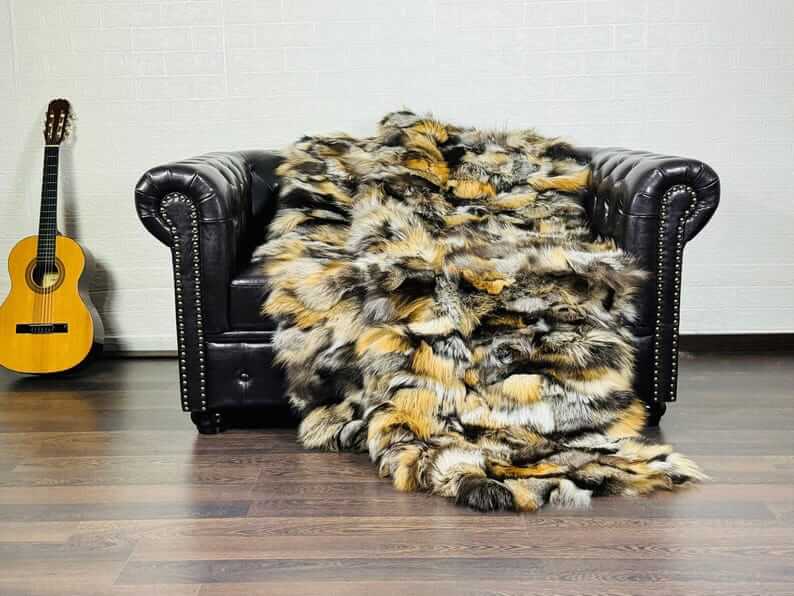 Fox Fur Blanket Throw Double Sided Gross Natural draped over a leather couch, showcasing vibrant orange, black, and silver colors.