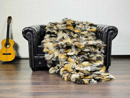 Fox Fur Blanket Throw Double Sided Gross Natural draped over a leather couch, showcasing vibrant orange, black, and silver colors.