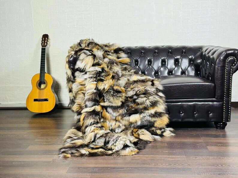 Fox Fur Blanket Throw Double Sided Gross Natural draped over a black sofa with a guitar in the background.