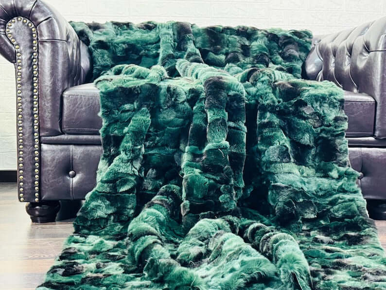 Rabbit Blanket Throw Rex Green Black - Tatifurs draped on a stylish leather sofa, showcasing its rich green-black hue.