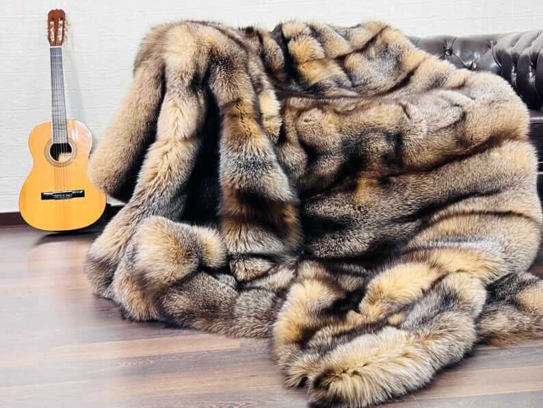 Natural Crystal Fox Fur Blanket - Tatifurs draped elegantly with a guitar in a cozy setting.