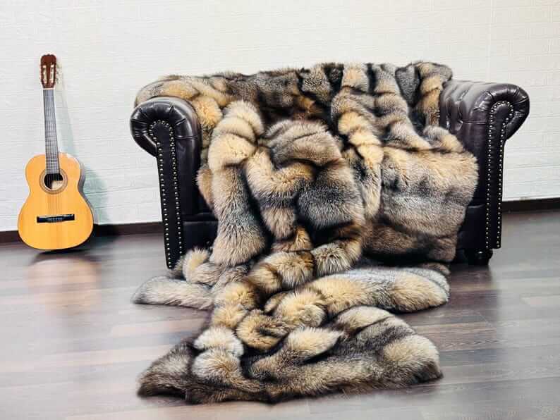 Natural Crystal Fox Fur Blanket - Tatifurs draped on couch beside guitar, showcasing its warm, earthy tones.
