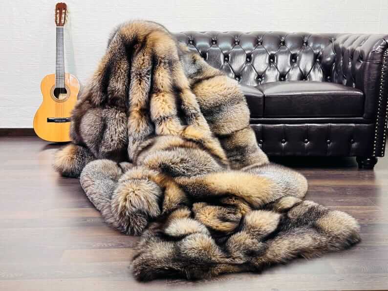 Natural Crystal Fox Fur Blanket - Tatifurs draped over a sofa with a guitar nearby, showcasing its luxurious texture and warmth.