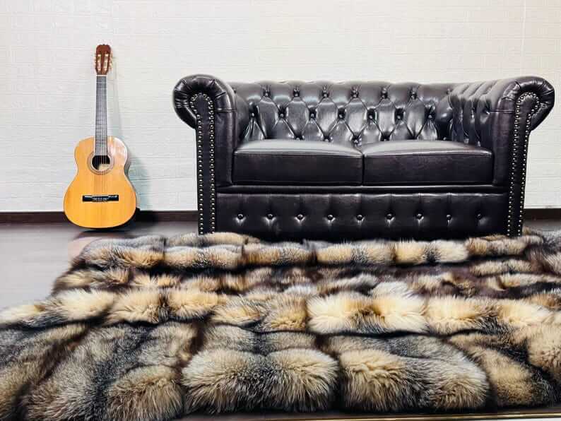 Natural Crystal Fox Fur Blanket - Tatifurs draped on a floor near a black leather couch and an acoustic guitar.