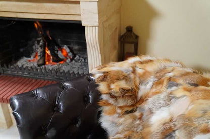 Fox Fur Blanket Throw Red Canadian - Tatifurs draped on a chair near a cozy fireplace.