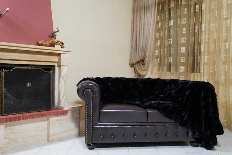 Rabbit Blanket Throw Rex Black - Tatifurs draped on a stylish leather sofa in a cozy living room.