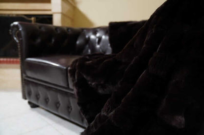 Rabbit Blanket Throw Rex Dark Brown - Tatifurs draped over a luxurious dark leather sofa.