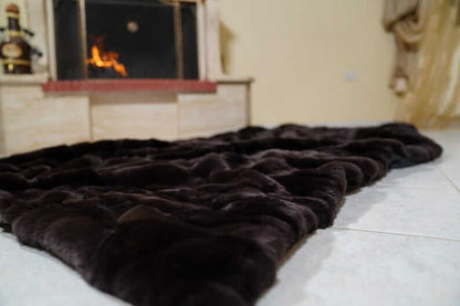 Rabbit Blanket Throw Rex Dark Brown - Tatifurs spread on the floor near a fireplace, showcasing its luxurious softness and rich color.