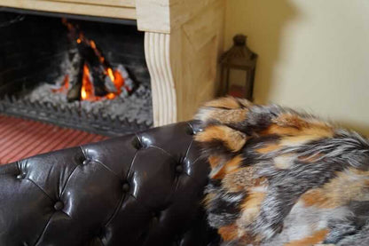 Fur Throw Blanket Natural Gross Fox – Luxury - Tatifurs draped on a stylish sofa near a cozy fireplace.