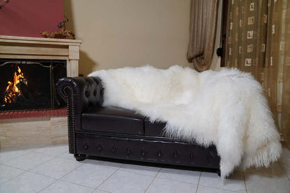 White Wool Sheepskin Mongolian Blanket Throw - Tatifurs draped over a black leather couch in a cozy living room setting.