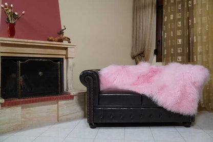 Wool Sheepskin Mongolian Blanket Throw Pink - Tatifurs draped over a black leather couch in a cozy living room.