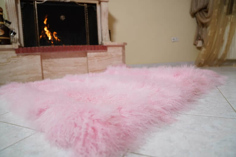 Wool Sheepskin Mongolian Blanket Throw Pink - Tatifurs displayed near a cozy fireplace in a warm setting.
