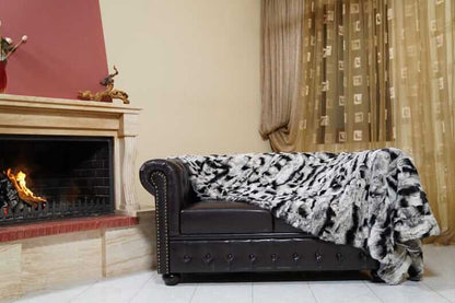 Rabbit Blanket Throw Chinchilla Rex - Tatifurs draped over a stylish couch near a fireplace in an elegant living room.