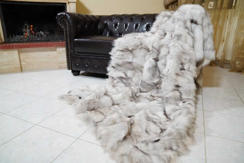 Fox Fur Blanket Throw Blue Natural - Tatifurs draped over a leather sofa, showcasing its luxurious texture.