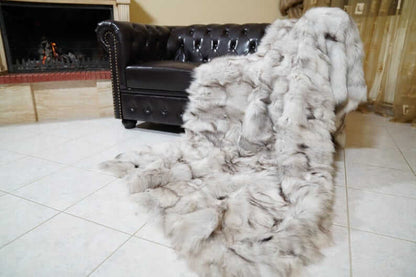 Fox Fur Blanket Throw Blue Natural - Tatifurs draped over a leather sofa, showcasing its luxurious texture.
