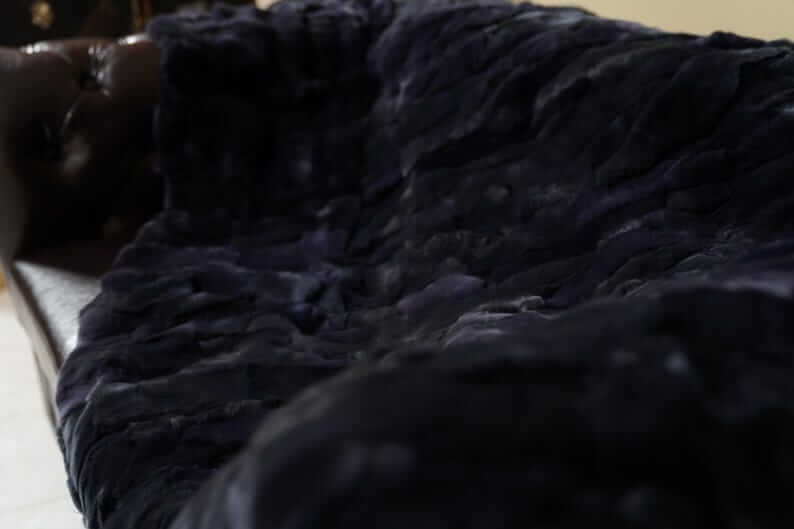 Double Sided Fur Rex Rabbit Blanket Throw Dark Blue draped on a couch, showcasing its rich midnight color and texture.