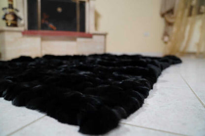 Rabbit Blanket Throw Rex Black - Tatifurs displayed in a cozy interior setting, showcasing its luxurious black fur texture.