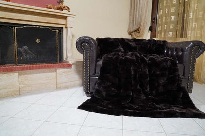 Rabbit Blanket Throw Rex Dark Brown - Tatifurs draped on a luxurious leather sofa in an elegant living room setting.