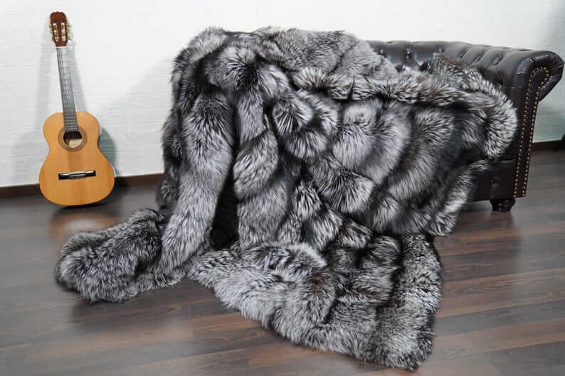 Fox Fur Blanket Throw Silver Natural - Tatifurs draped over a couch with a guitar in the background, showcasing luxury and elegance.