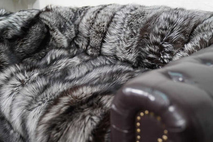 Fox Fur Blanket Throw Silver Natural - Tatifurs displayed on a luxurious couch, showcasing its soft, elegant texture and silver sheen.