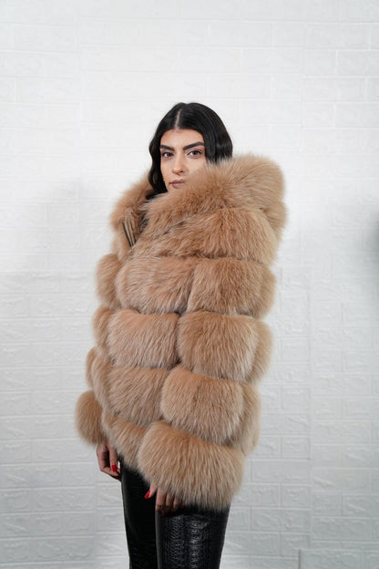 Model wearing camel brown fox fur coat with hood and leather accents
