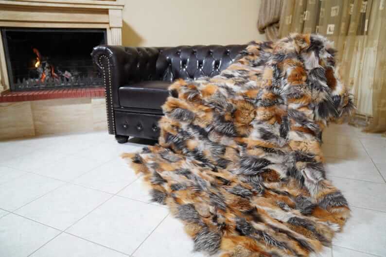 Fur Throw Blanket Natural Gross Fox – Luxury - Tatifurs displayed on a couch near a fireplace.