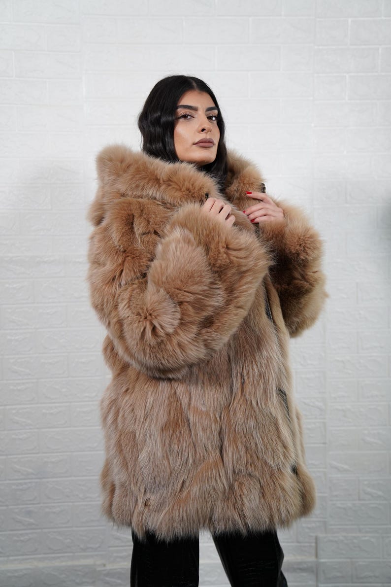 Model wearing camel brown fox fur coat jacket with hood and zipper
