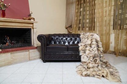 Fox Fur Blanket Throw Double Sided Iceberg Beige draped over a stylish leather sofa by the fireplace.