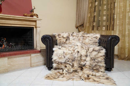 Fox Fur Blanket Throw Double Sided Iceberg Beige draped over a sofa near a fireplace, showcasing its luxurious texture.
